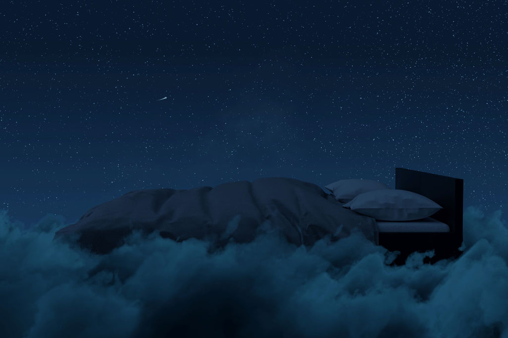 An image of a bed floating on clouds. It's nighttime and the sky is clear and star-flecked. 