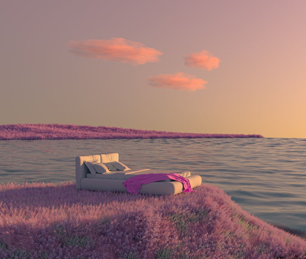 An image of a bed on a field of lavender with the sea all around. The sun is rising.